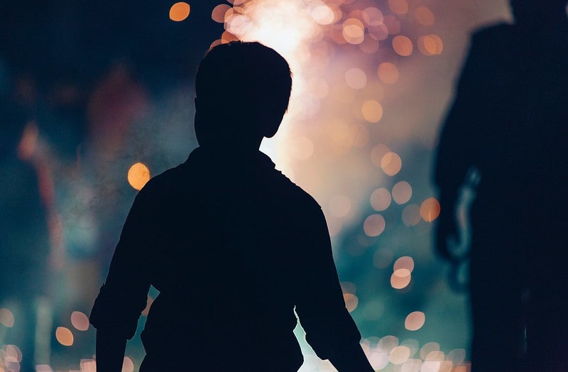 Silhouette of a boy looking on at a crackling bonfire for Bonfire Night.