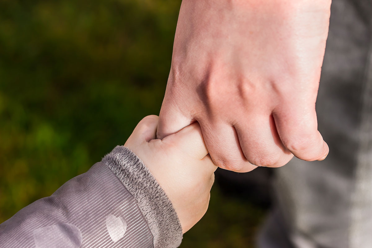 A close up image of a small baby's hand holding an adult's hand.