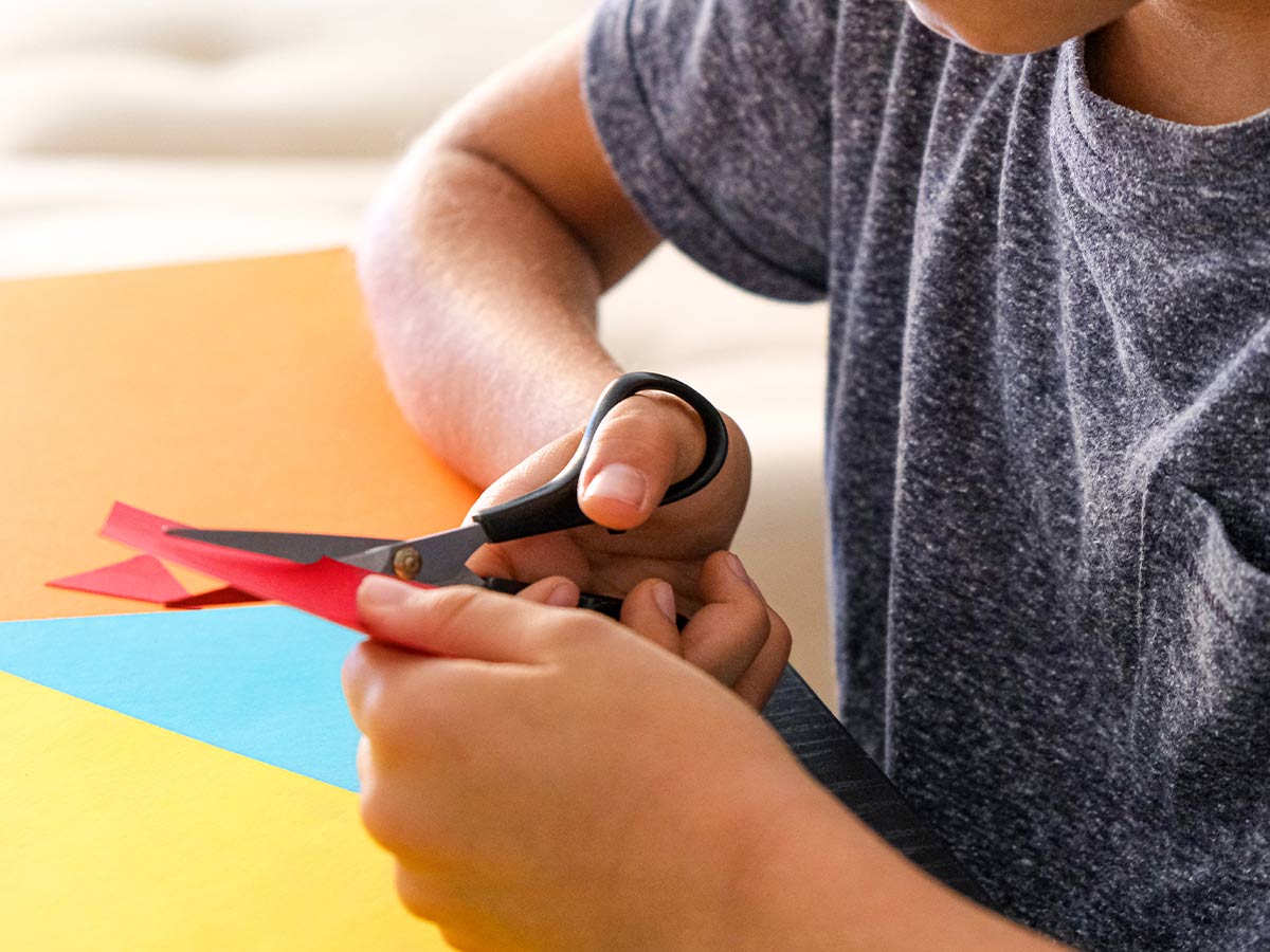 Close up of a child cutting coloured paper to make origami animals.