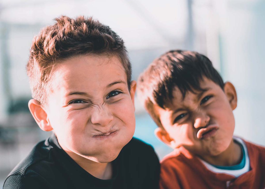 Two boys pull funny faces at the camera as they laugh at a New Year joke.