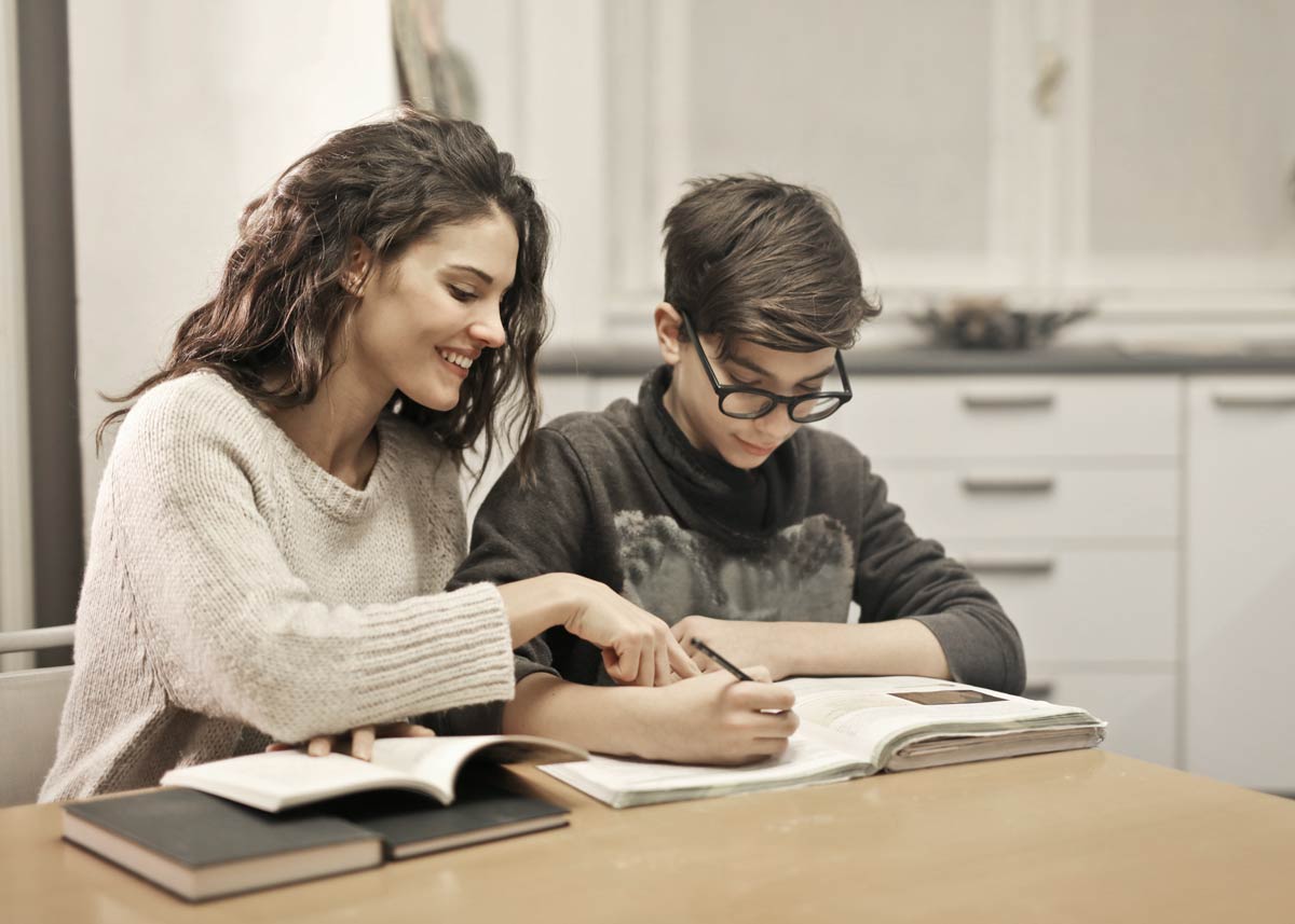 Mum sat at the table with her son smiling as she helps him solve rhyming riddles.