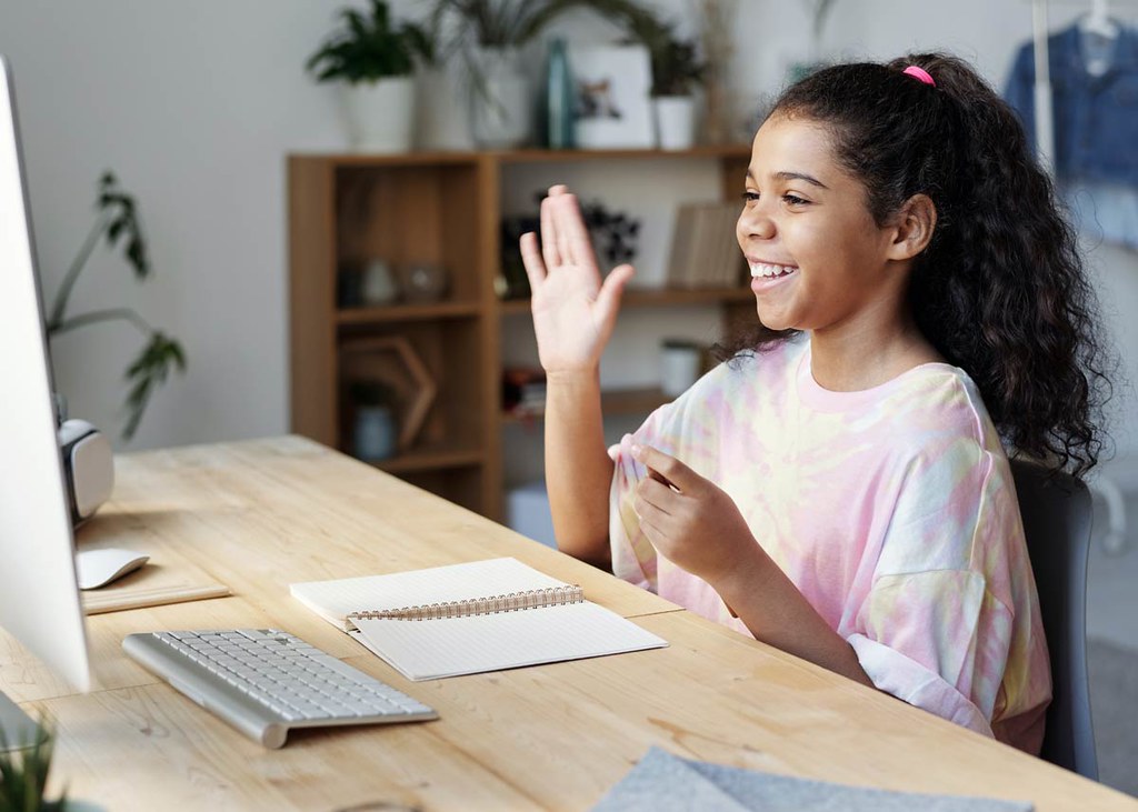 A young girl smiles at her computer screen as she reads pen puns.