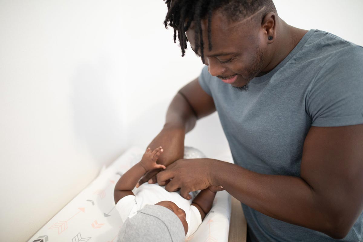 A dad smiles at his baby as he changes its nappy.