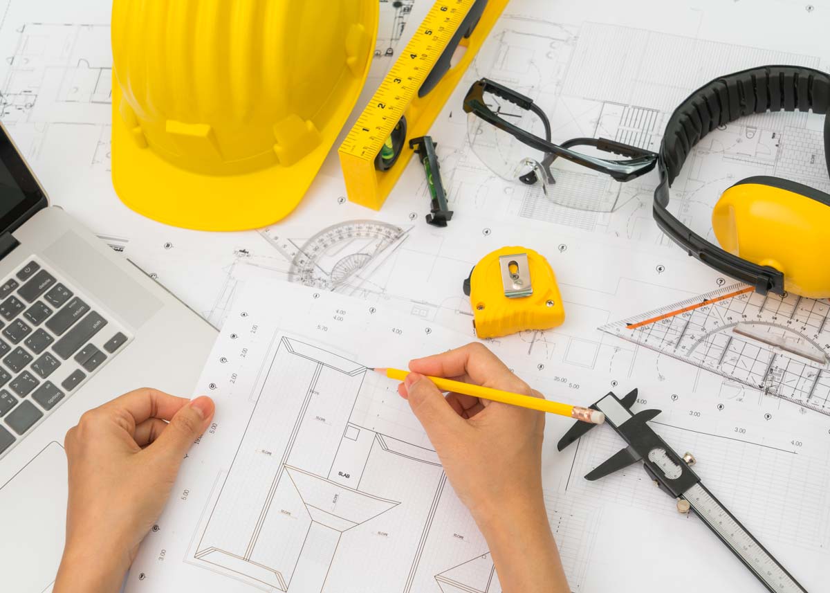 An engineer's desk: their tools, a hard hat and sketched diagrams.