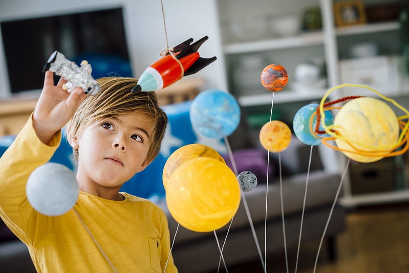 Young boy exploring the planets playing with his homemade planetarium.