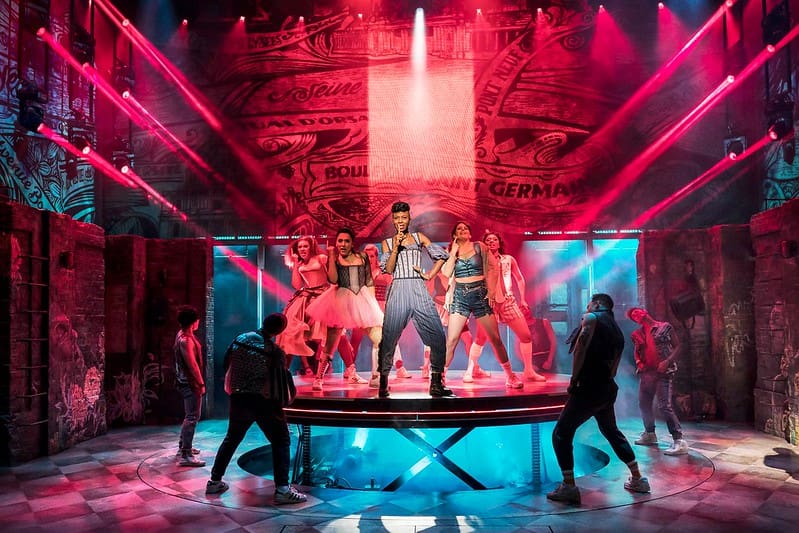 A song and dance sequence in & Juliet performed under red and blue lighting.