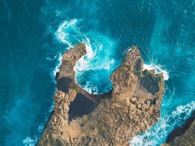 An aerial view of vast ocean and an island with a dungeon.