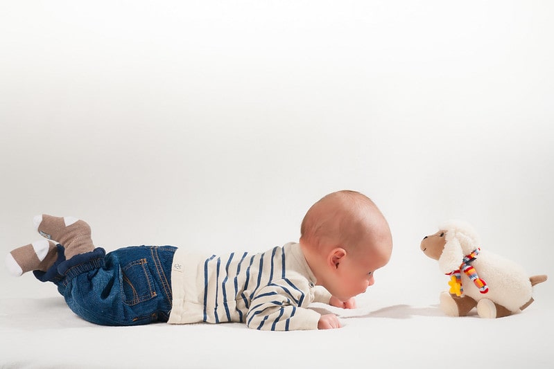 Charming little boy happily playing with his plush toy.