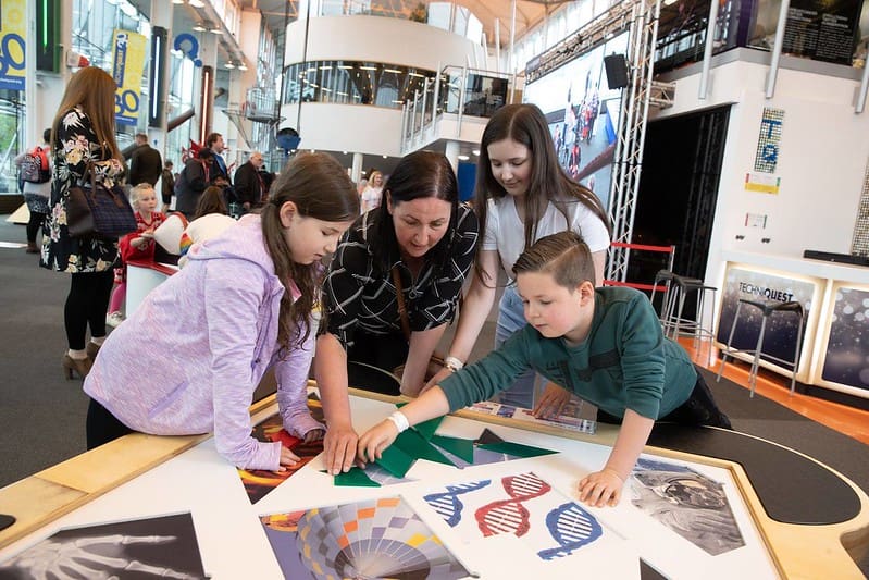 A family at the Techniquest science museum looking at an exhibit together.