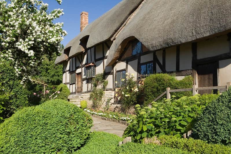 A close up picture of Anne Hathaway's Cottage next to a blossom tree.
