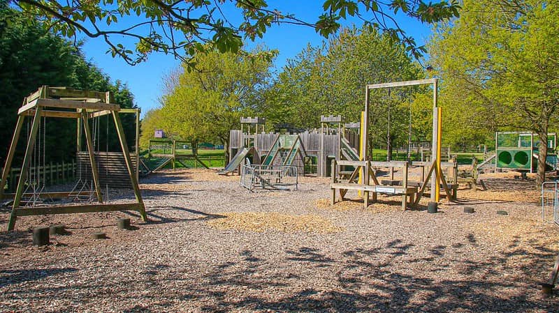 A wooden play area at Robin Hoods Wheelgate Park with swings, slides and tunnels.