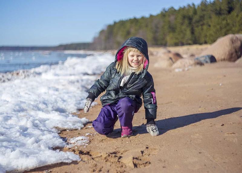 Finnish girl happily playing at the sea shore.