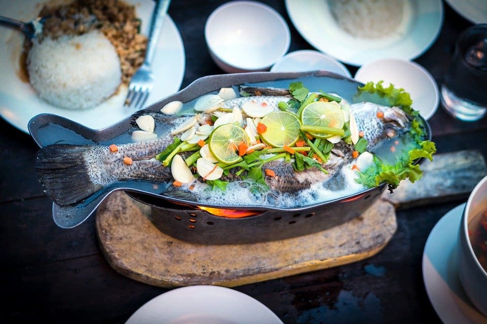 Fish in a plate covered with lemon slices and other vegetables