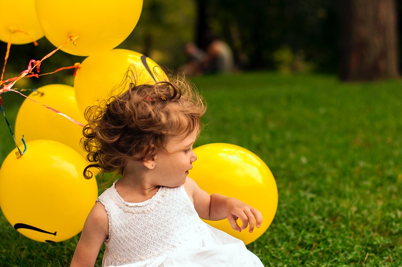 Girl whose name is inspired by yellow next to yellow balloons.