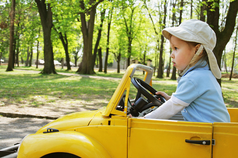 Child in yellow car driving.