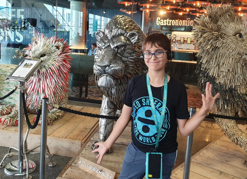 Young boy stood by three lion statues.