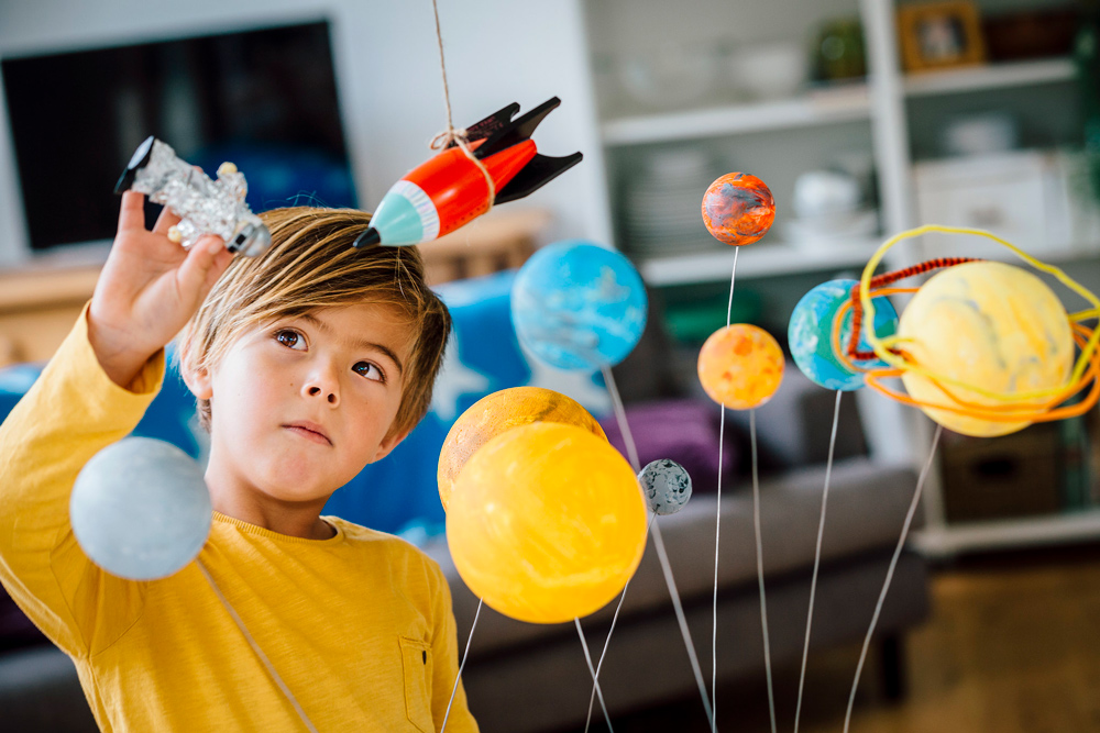 Boy playing with solar system project.