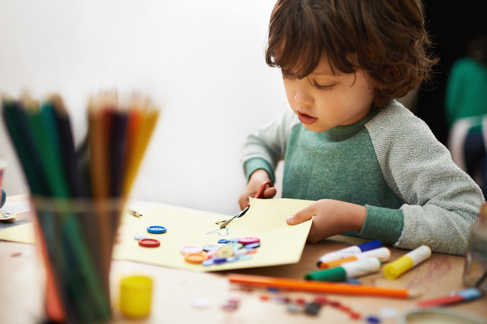 A boy cutting out paper for a space-themed craft activity..