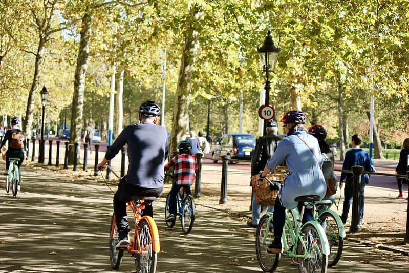 A group of people cycling through a park in London.
