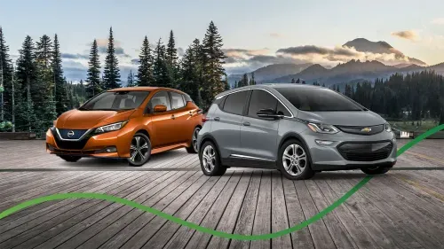 nissan leaf and chevy bolt on a deck with mountain background