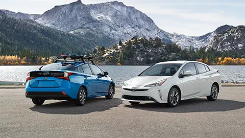 Two Priuses parked with mountain backdrop