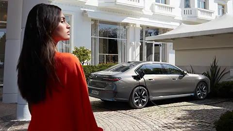 woman looking at BMW i7 in driveway