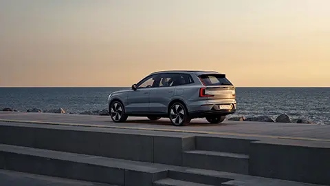 un volvo ex90 estacionado en un muelle de cemento con vista al océano