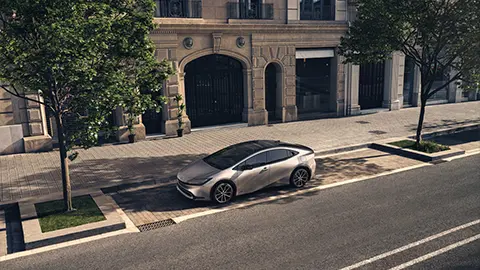 un toyota prius de quinta generación estacionado en la calle frente a un edificio de la ciudad