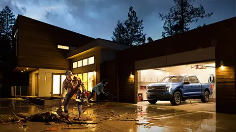 Couple cleaning up debris in driveway, with F-150 parked in garage