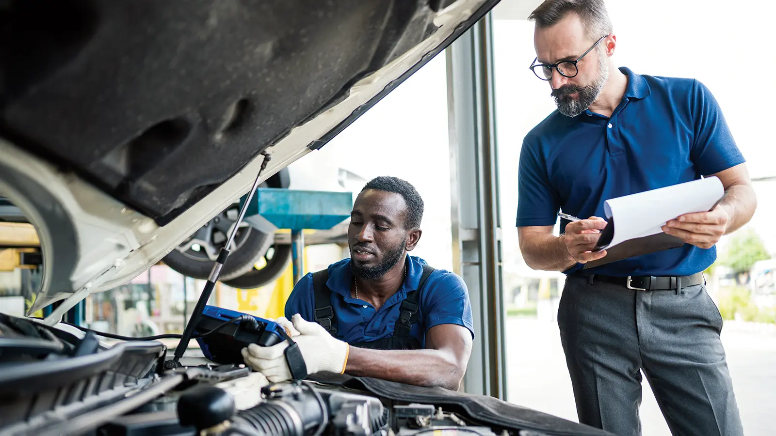 Technicians looking at car engine