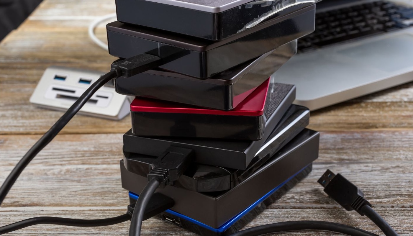 A stack of external hard drives next to a laptop computer.