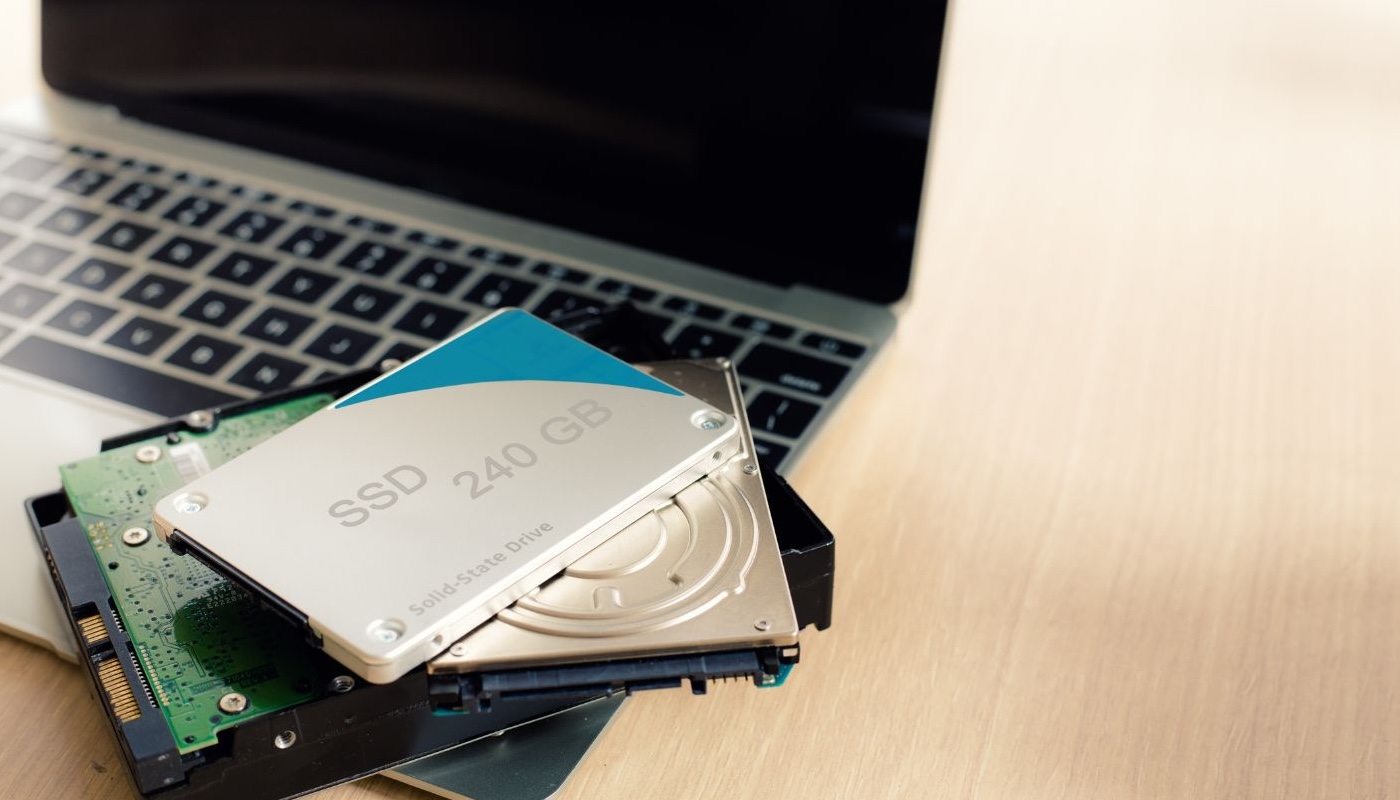 Different external and internal hard drives stack on top of a laptop computer.