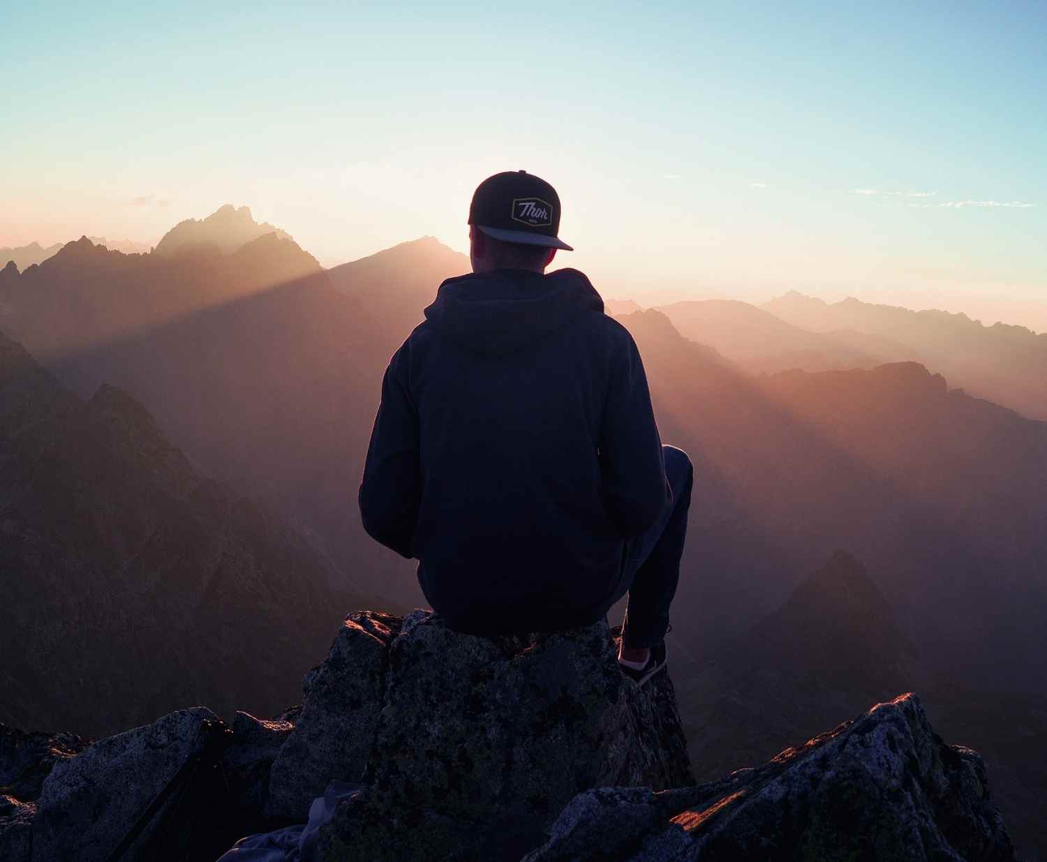 Man sitting on a mountain looking out at a view