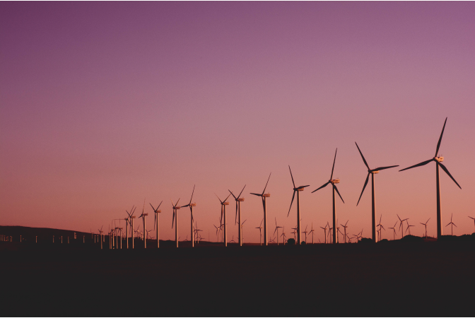A line of Wind turbines against a pink sky