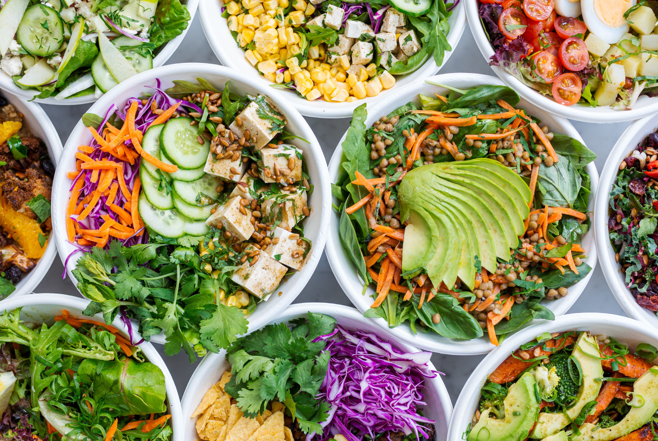 Top view of assorted vegetarian salads in bowls, all of which can be eaten as part of a plant-based diet.