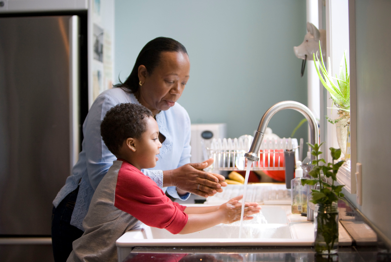 Mother and small child washing hands at the sink