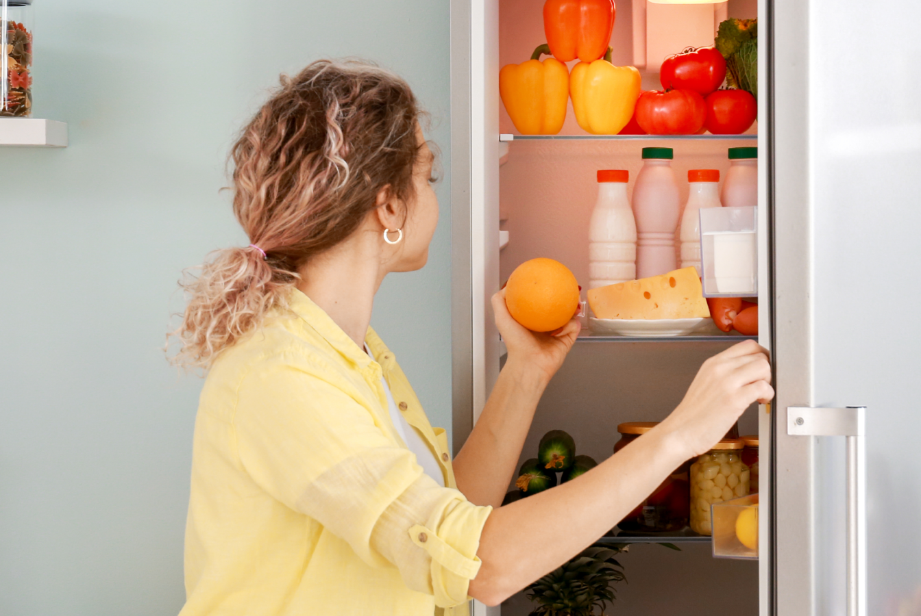 Woman opening fridge to retrive an orange