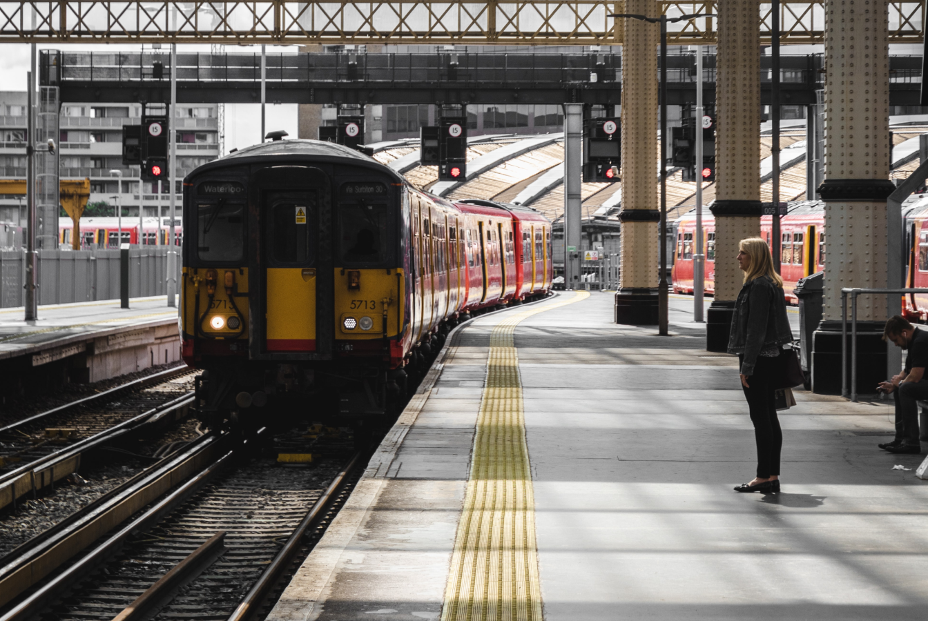 Subway train pulling into the station as a woman waits on the platform