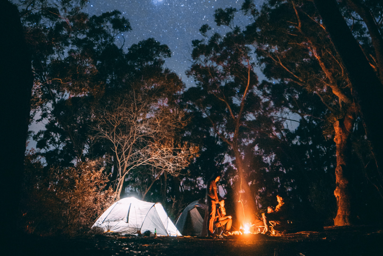 Four campers around a fire a night with a tent