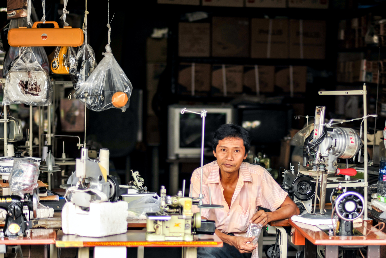 Older man sitting at a bank of sewing machines