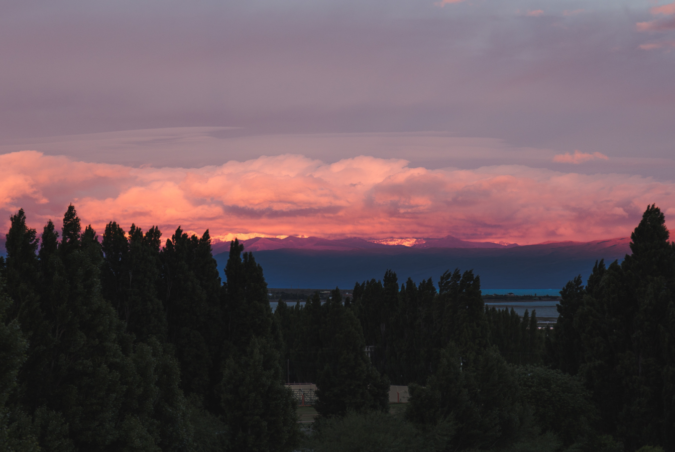 Sun setting behind snowy mountains clouds, overhead