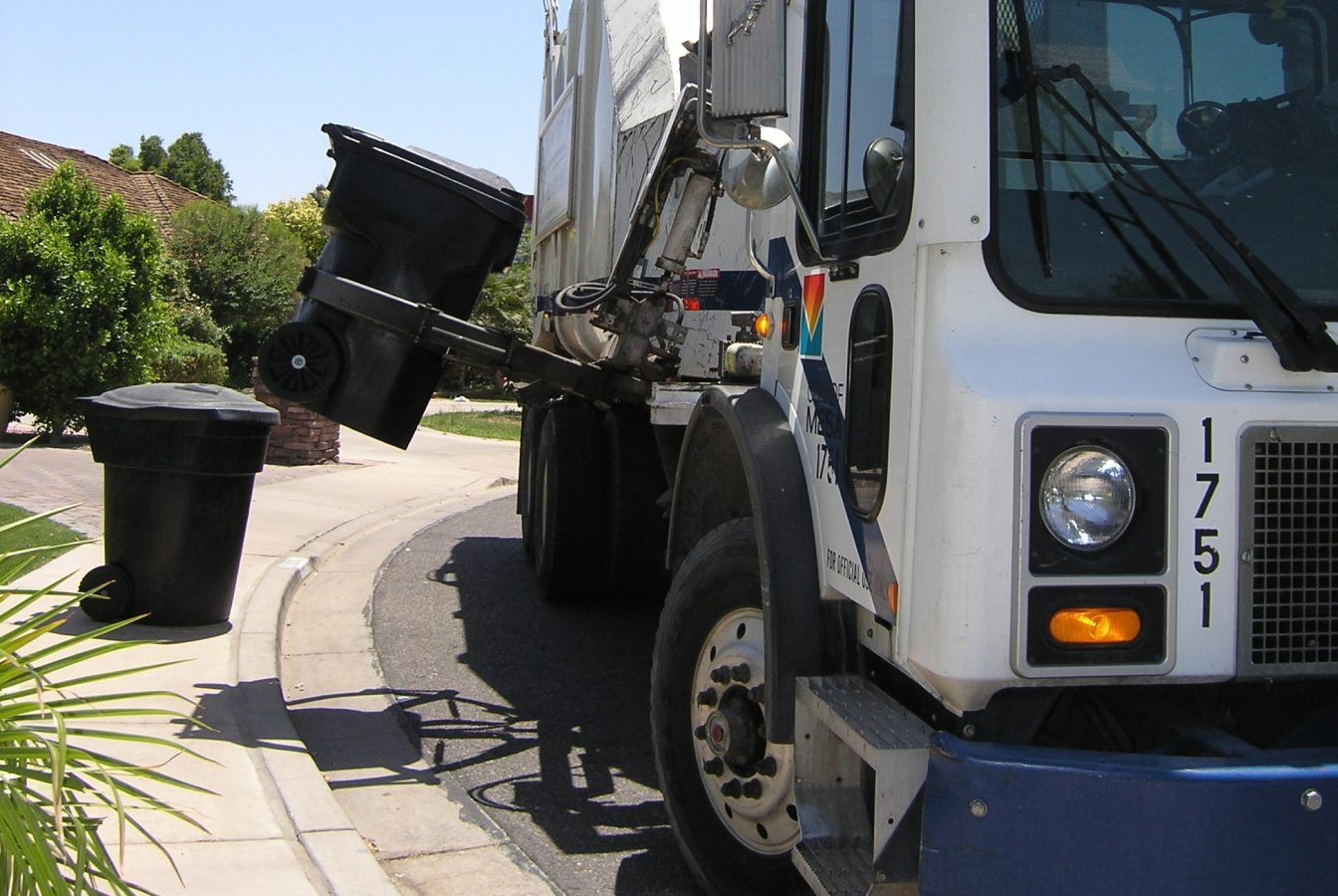 Mechanized garbage truck picking up bin