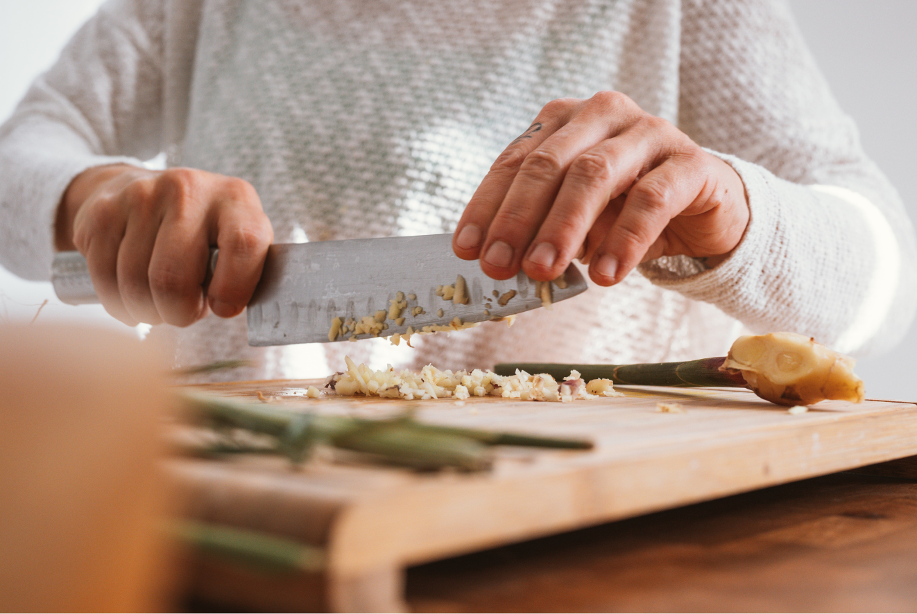 A person chopping raw ginger for a vegan dish