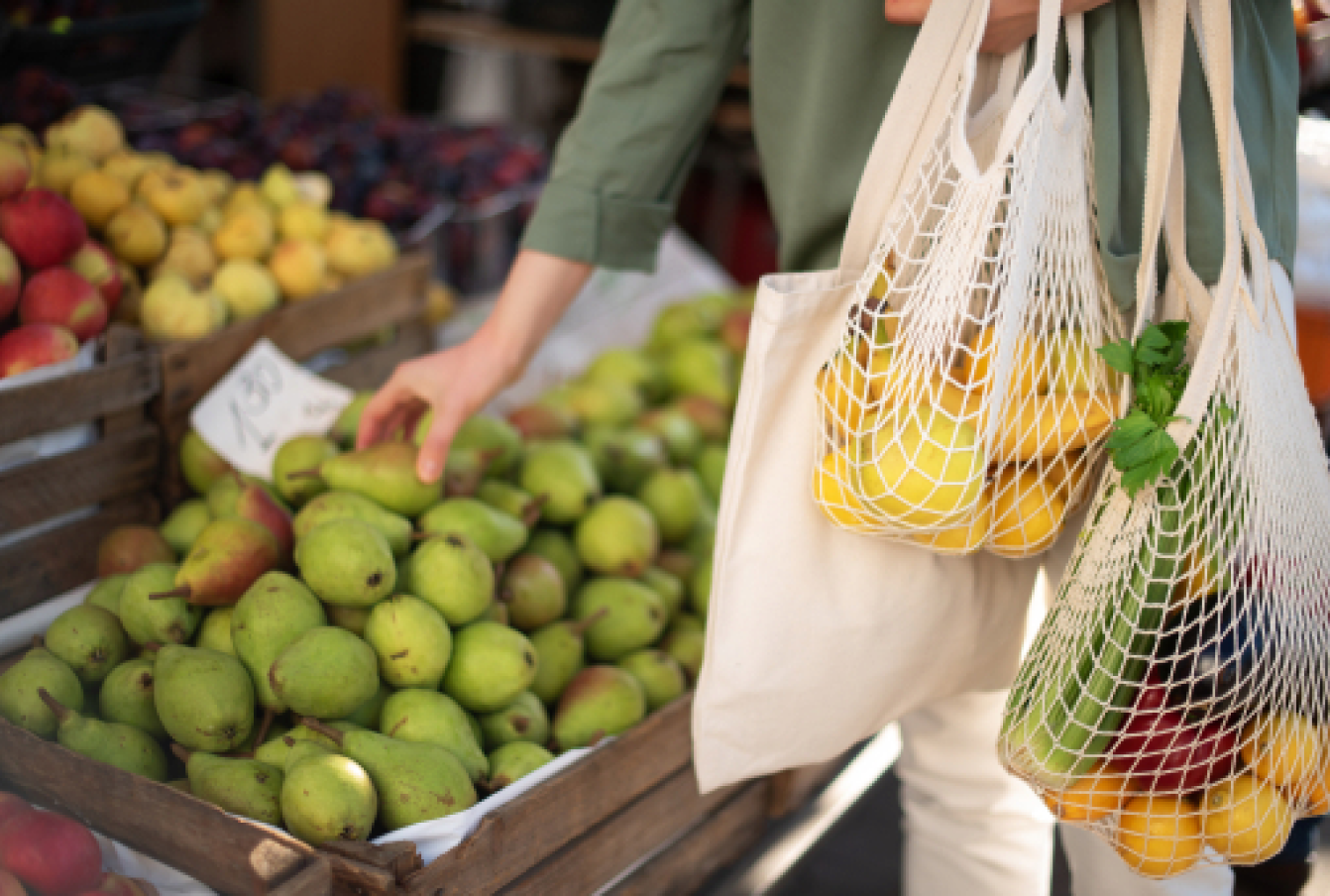 A lady using tote bags rather than plastic ones to buy produce.