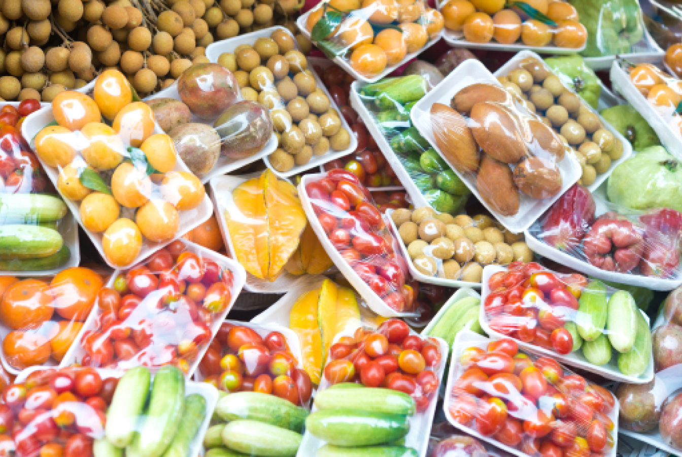 Plastic-wrapped fruits and vegetables at a grocery store.