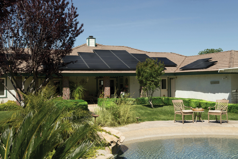 Solar panels cover the roof of a bungalow on a sunny day