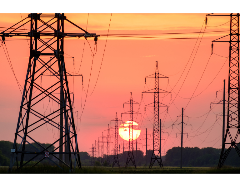 Power lines silhouetted against an orange sunset