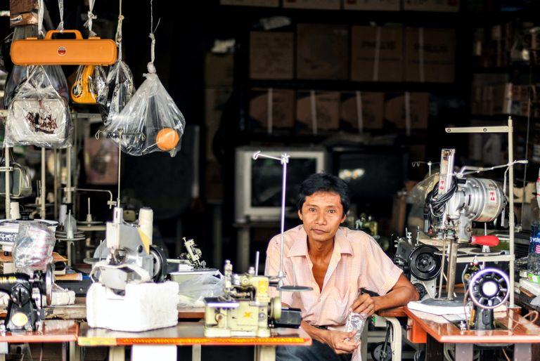 Older man sitting at a bank of sewing machines