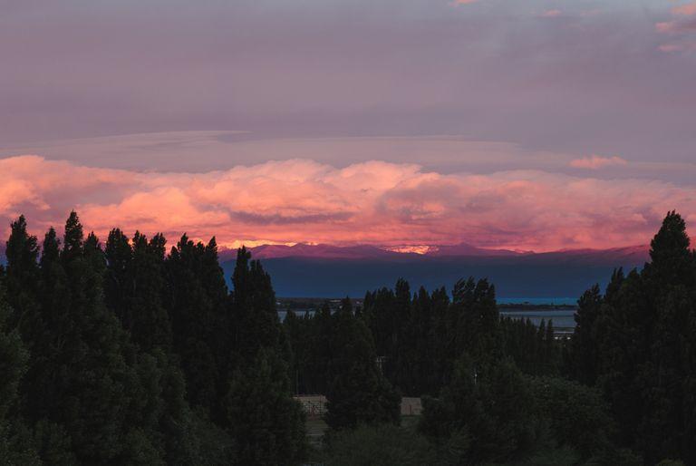 Sun setting behind snowy mountains and clouds overhead