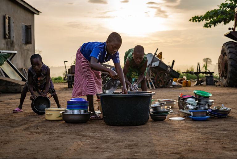 Kids washing dishes in a basin